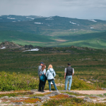 FAMILY LOOKING OUT TO ALASKAN BACK COUNTRY WITH MOUNTAIN RANGE IN DISTANCE