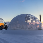Arctic truck parked next to the dome at sunset
