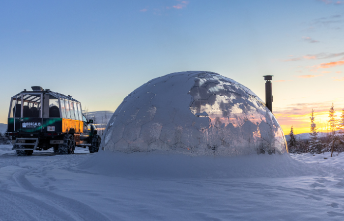 Arctic truck parked next to the dome at sunset