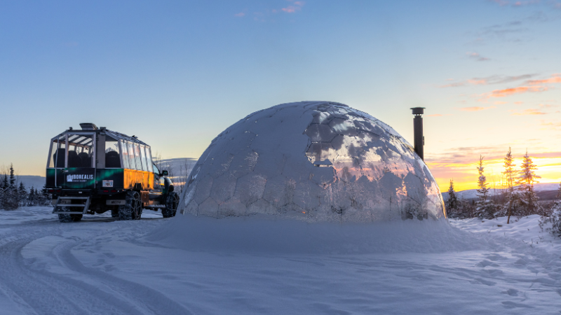 Arctic truck parked next to the dome at sunset